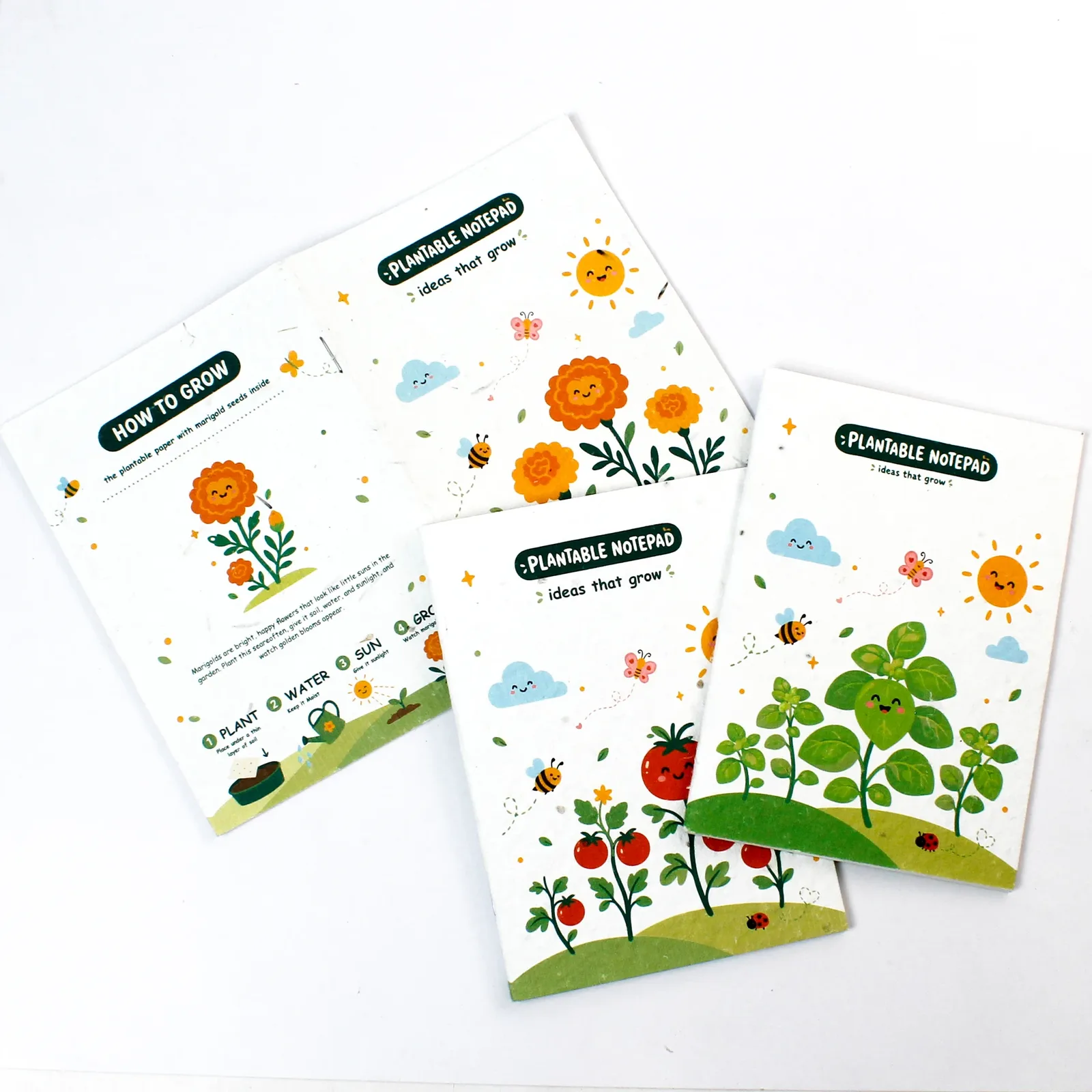 The three kids plantable notepads laid out to show illustrated covers and a planting-instruction reverse panel