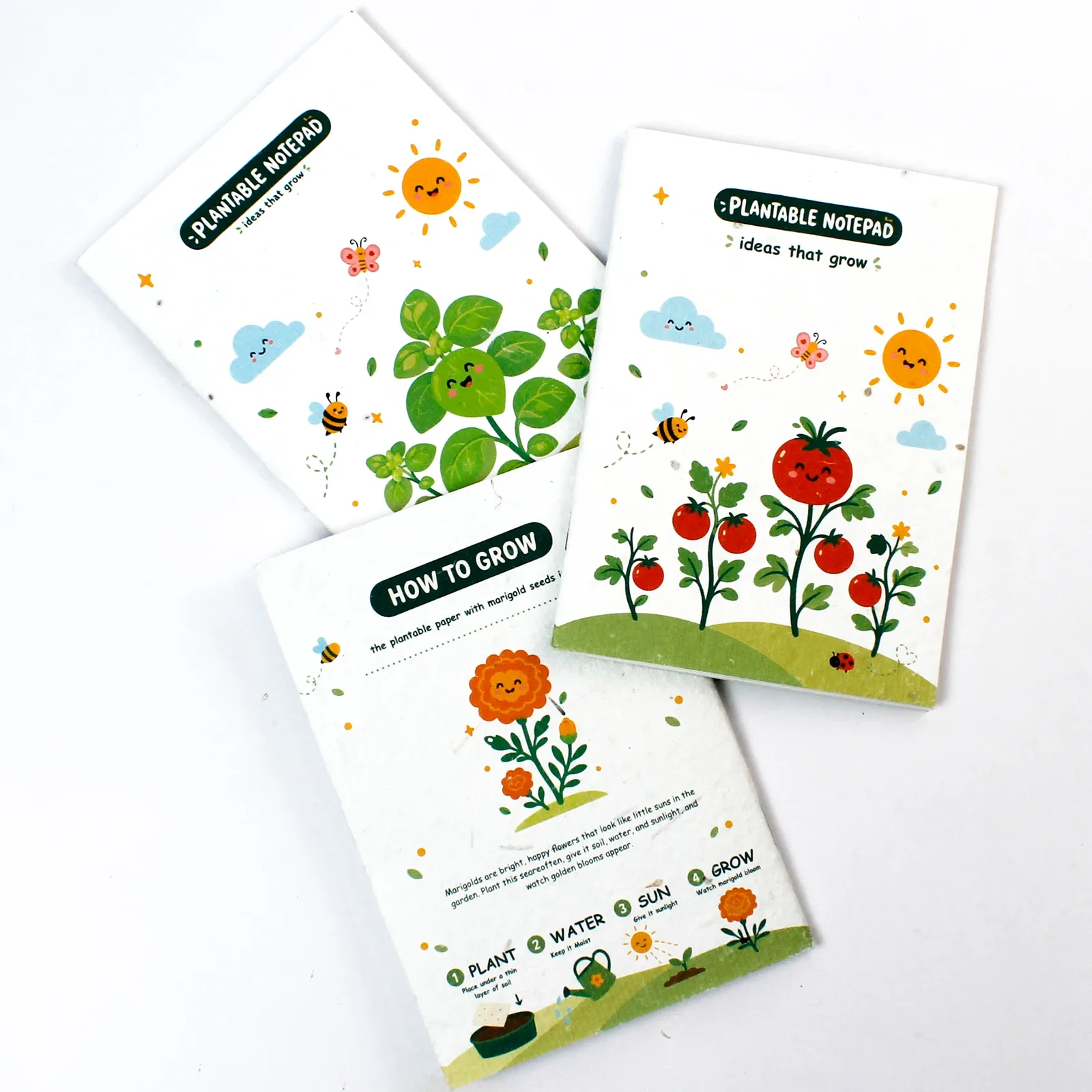Angled layout of the three illustrated plantable notepads showing cover and reverse designs