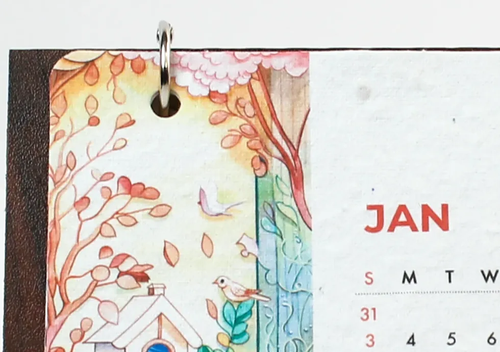 Close view of the illustrated January 2027 seed-paper calendar card and its metal binding ring