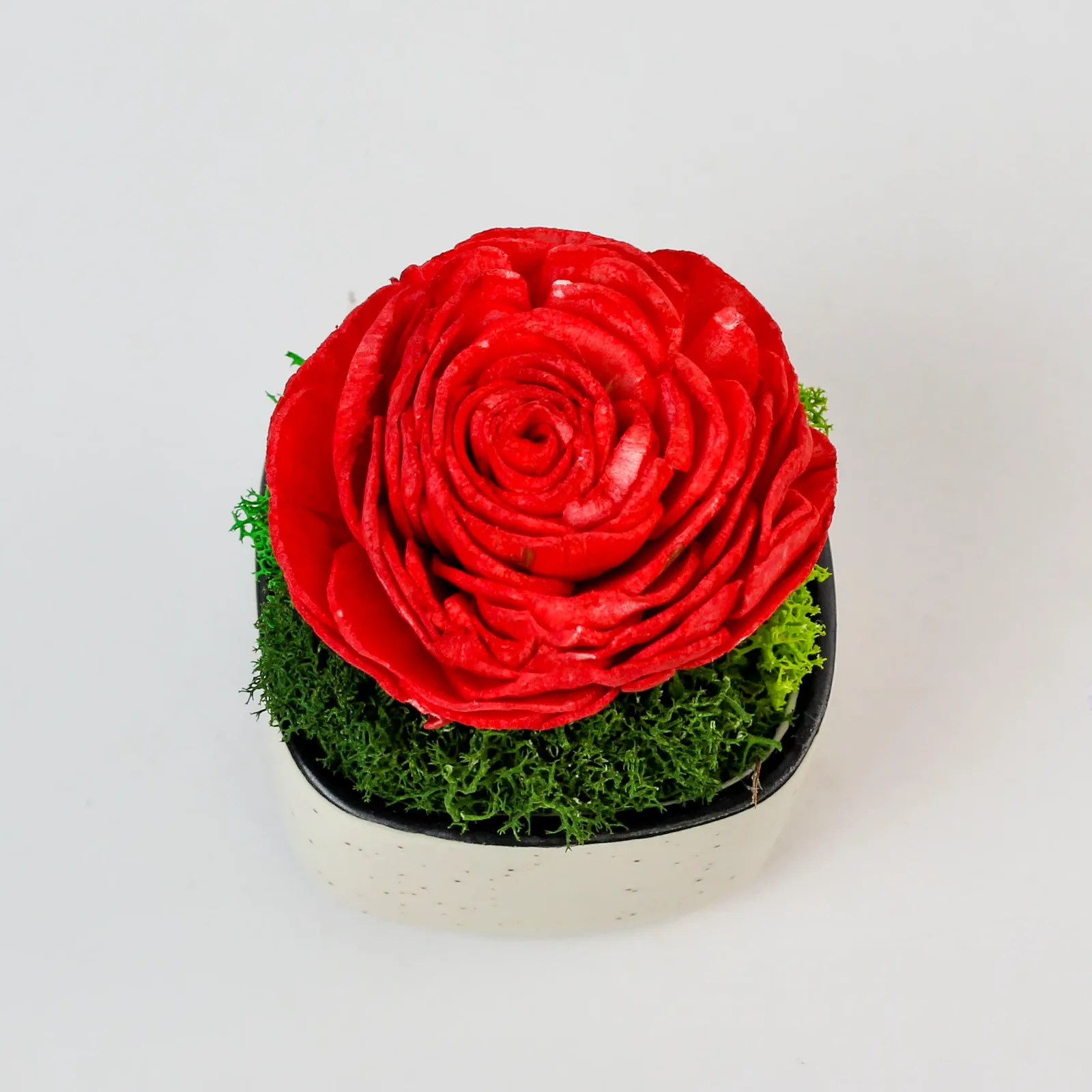 Overhead close-up of the red shola rose petals and preserved moss in the ceramic bowl