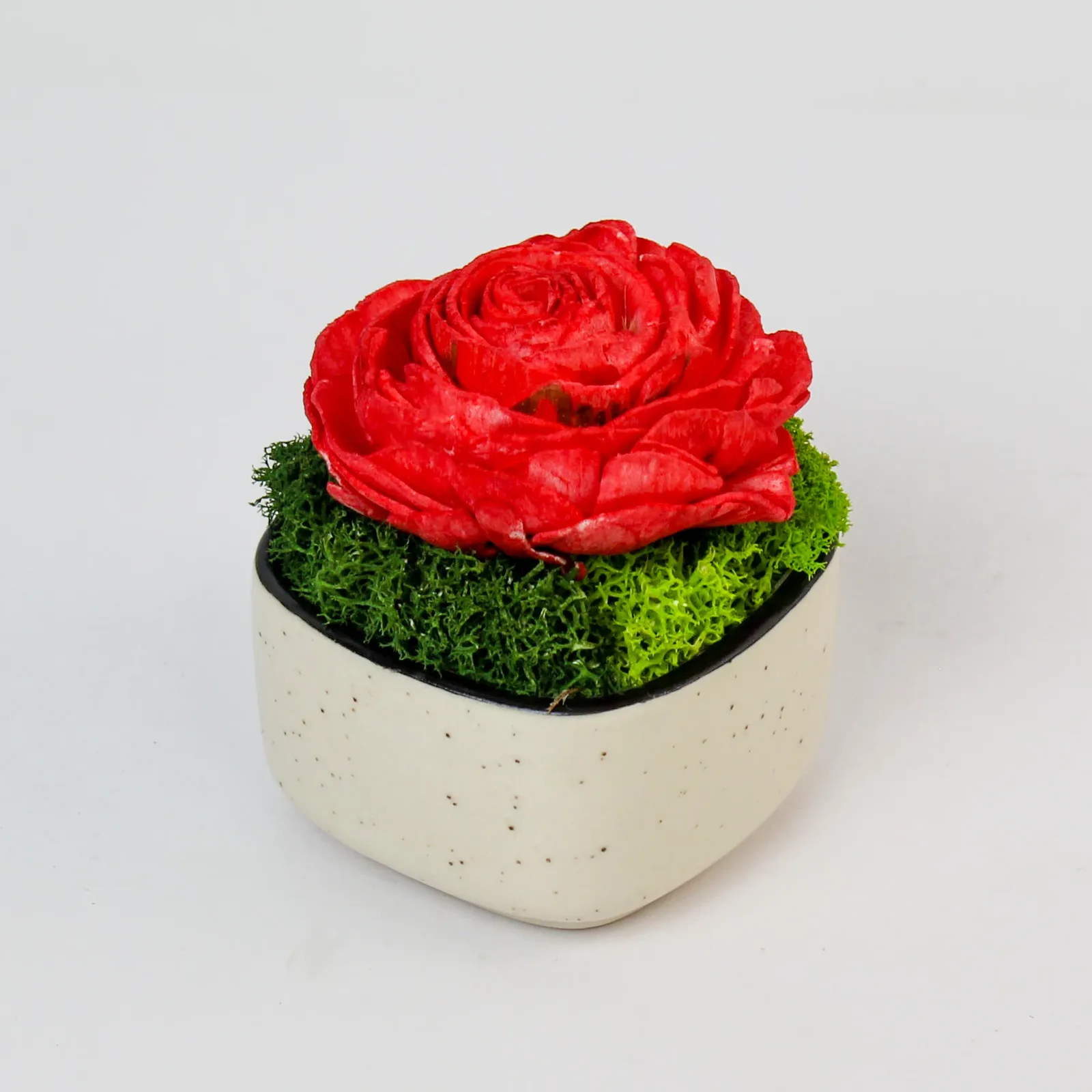 Angled view of the speckled ceramic rose pod showing its black inner lip and moss