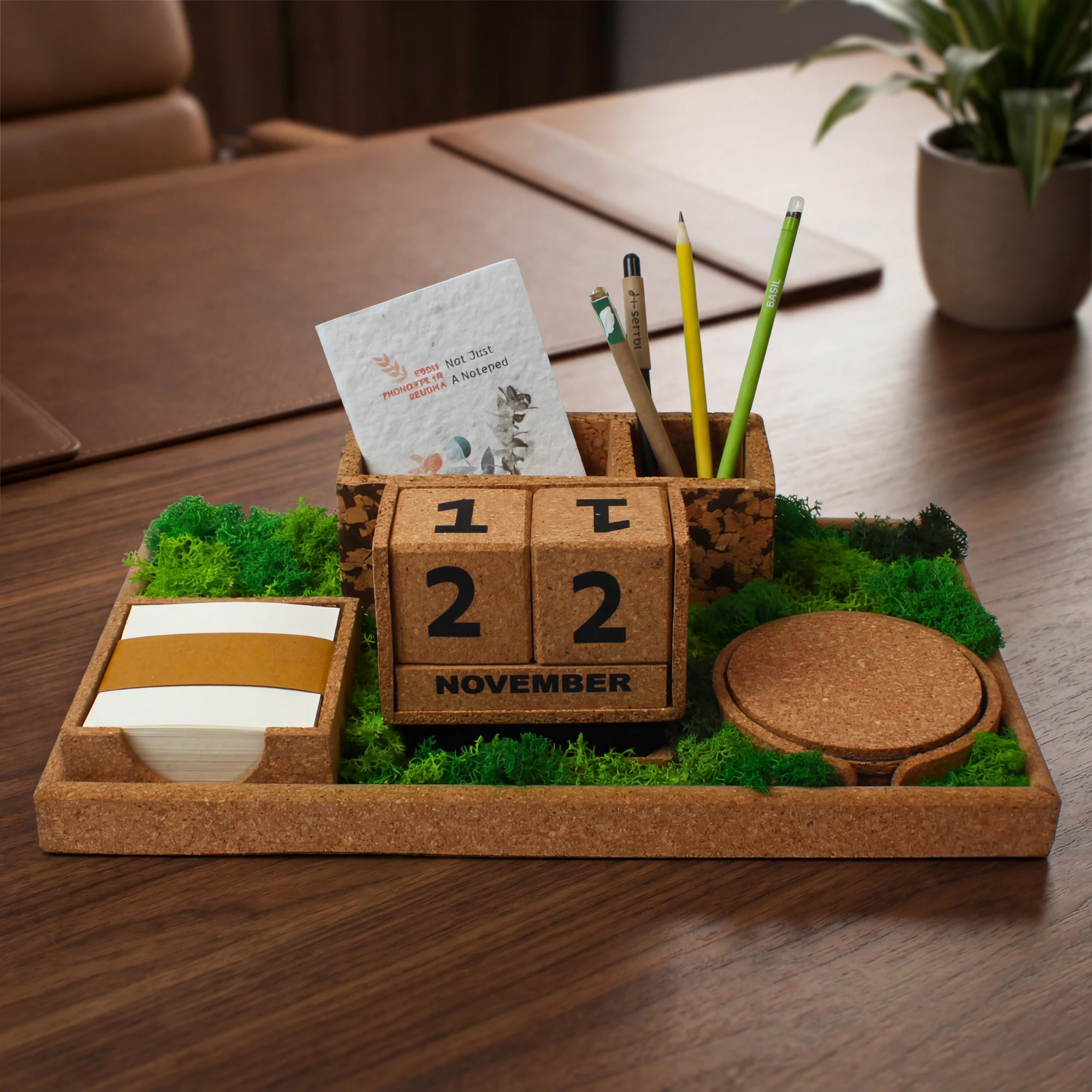 The Grove Executive XL cork tray on a wooden desk, with calendar blocks, notes, pens and moss