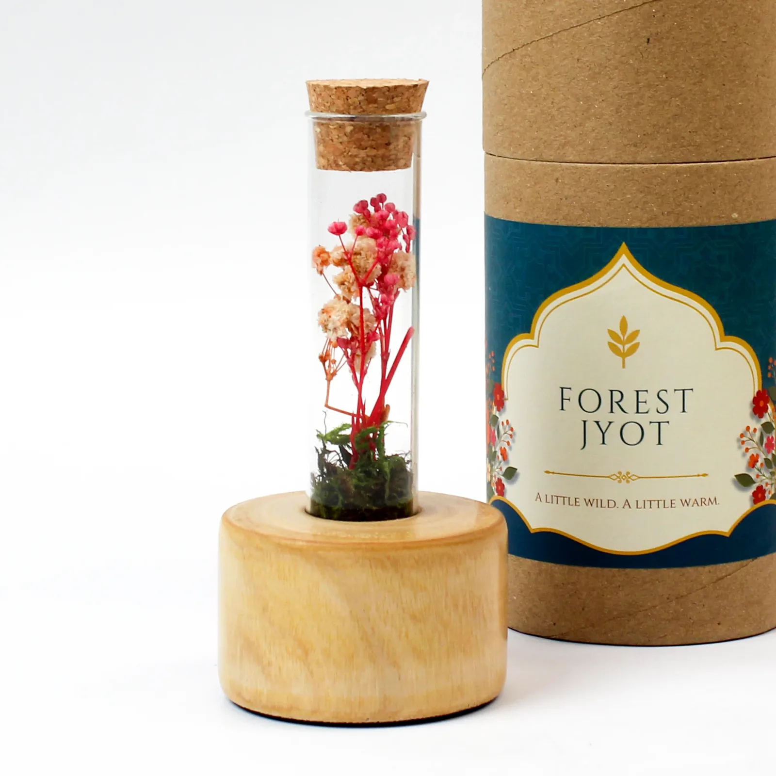 Close view of the Forest Jyot paper tube beside the preserved botanical glass bottle on a wooden stump
